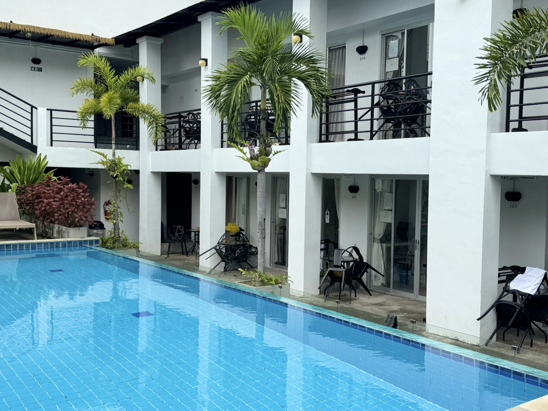 Pool running along the white guest buildings and garden